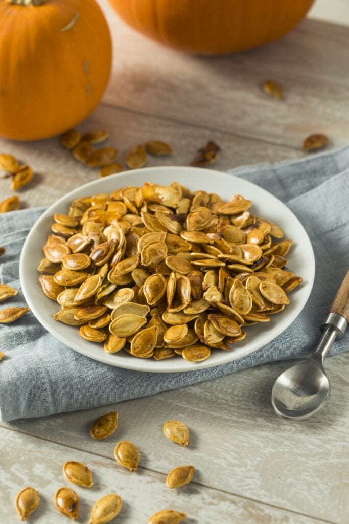 25 Rich Pumpkin Seed Recipes (+Easy Snacks): Roasted Pumpkin Seeds in a White Plate