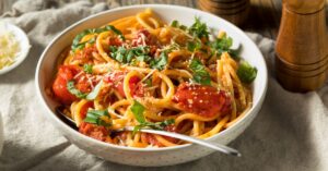 Tasty Bucatini Pasta with Tomatoes and Basil in a White Bowl