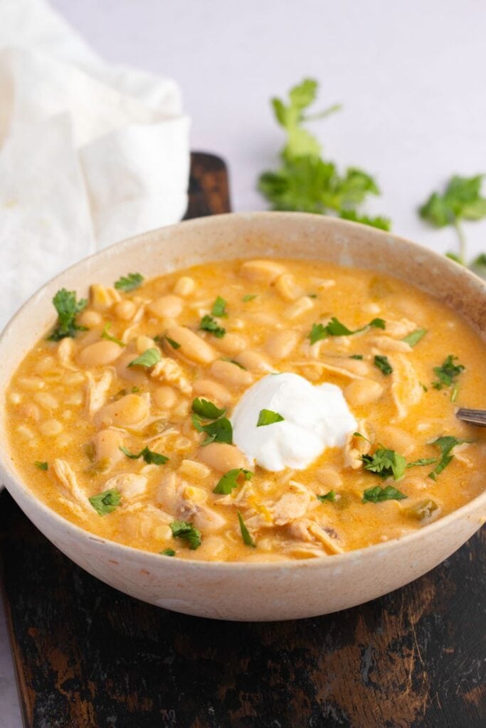 Warm Chicken Chili with Sour Cream and Herbs in a Bowl