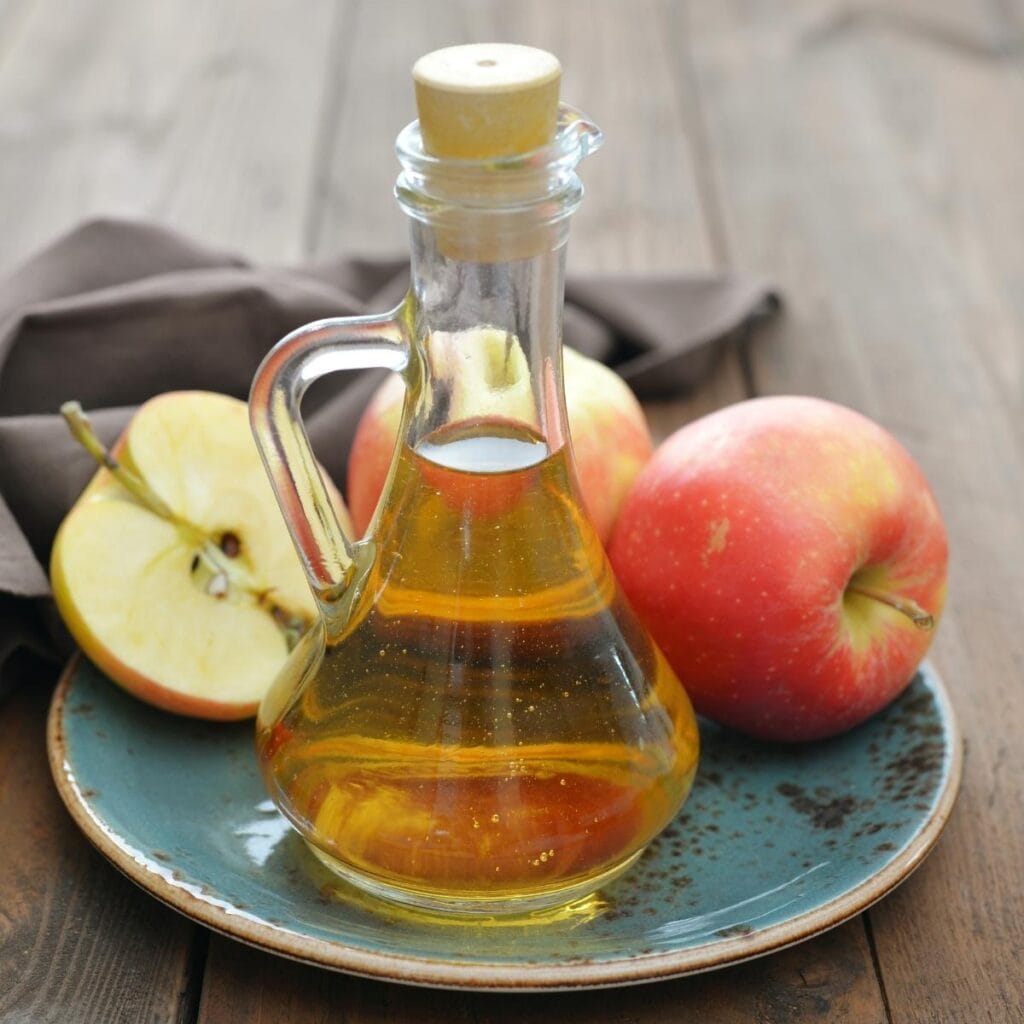 Apple Cider Vinegar in a jug on a plate with apples