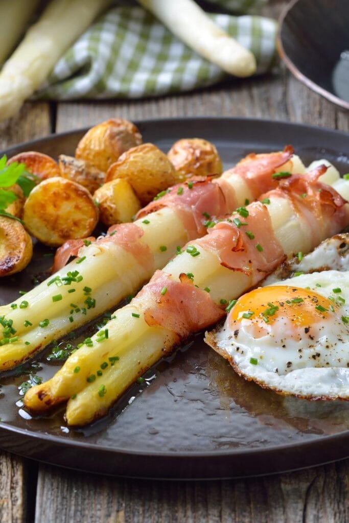 Baked White Asparagus Wrapped in Bacon with Potatoes and Egg