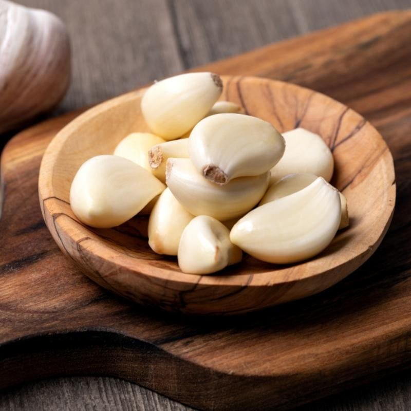 Peeled garlic cloves on a wooden plate