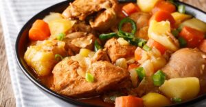 Homemade Chicken Stew with Green Onions, Carrots and Potatoes in a Black Plate