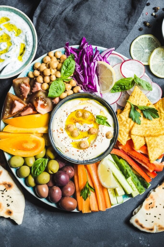 Hummus Dip in a Bowl with Vegetable Sticks, Chickpeas, Olives, Pita and Chips