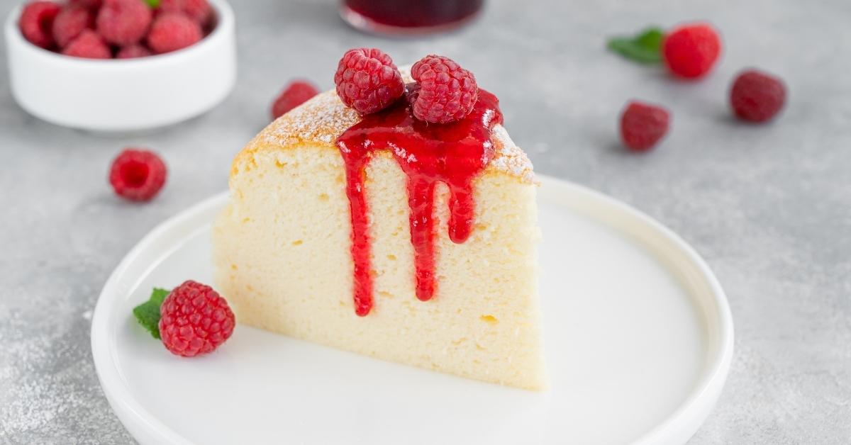 Slice of Homemade Japanese Cotton Cheesecake with Powdered Sugar, Raspberries and Sauce