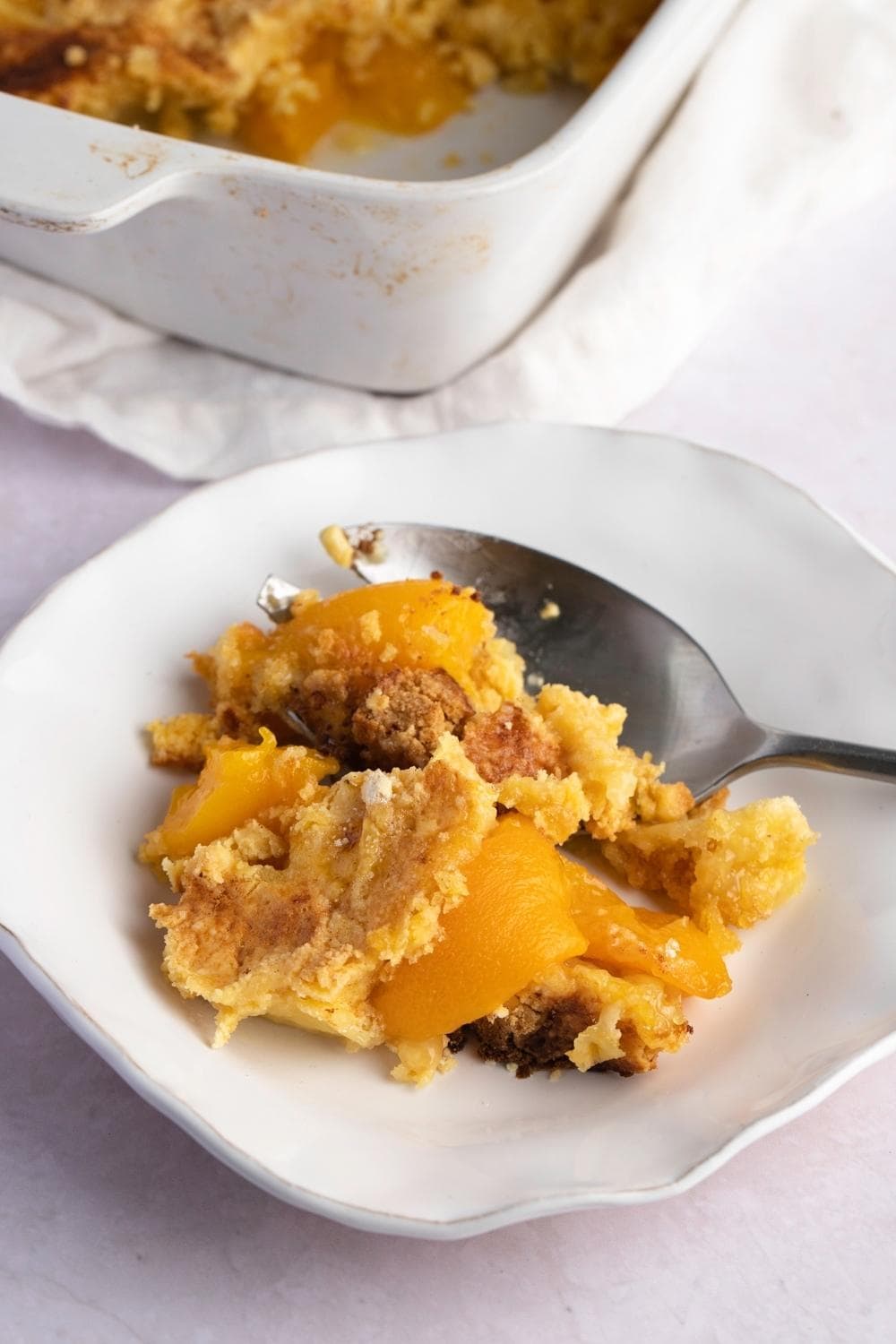 A Slice of Peach Dump Cake on a White Small Plate
