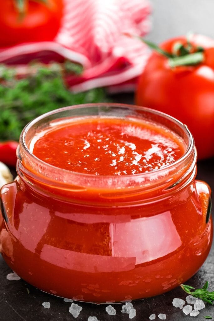 Tomato Puree in a Glass Jar with Fresh Tomatoes