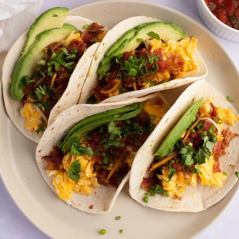 Breakfast  Tacos With Avocado Slices, Bacon and Eggs Garnished With Green Onions and Cilantro