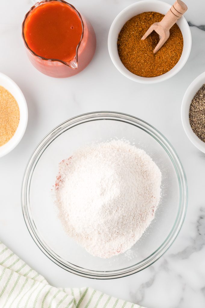 A mixture of flour, paprika, and cayenne pepper in a glass mixing bowl, top view.