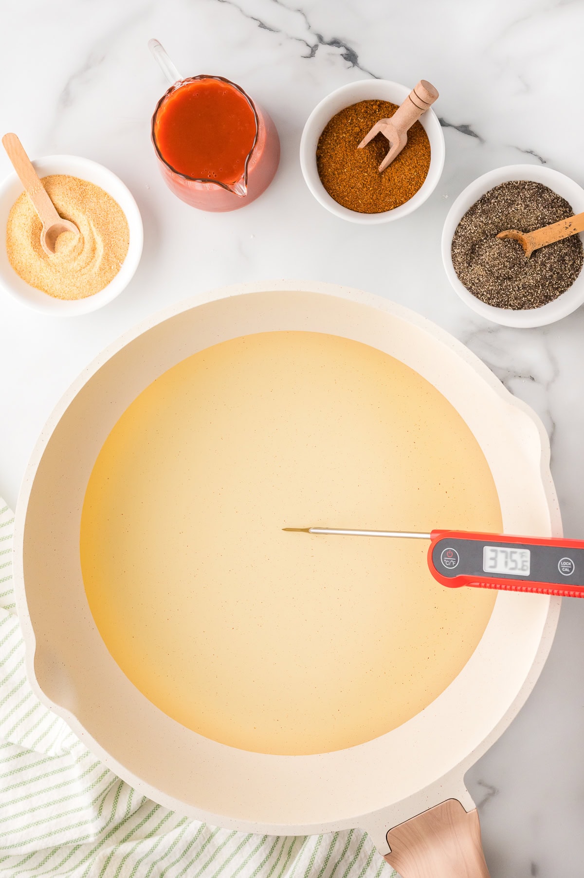 A large pot of hot oil, with a thermometer showing the temperature, and spiced on the side, top view