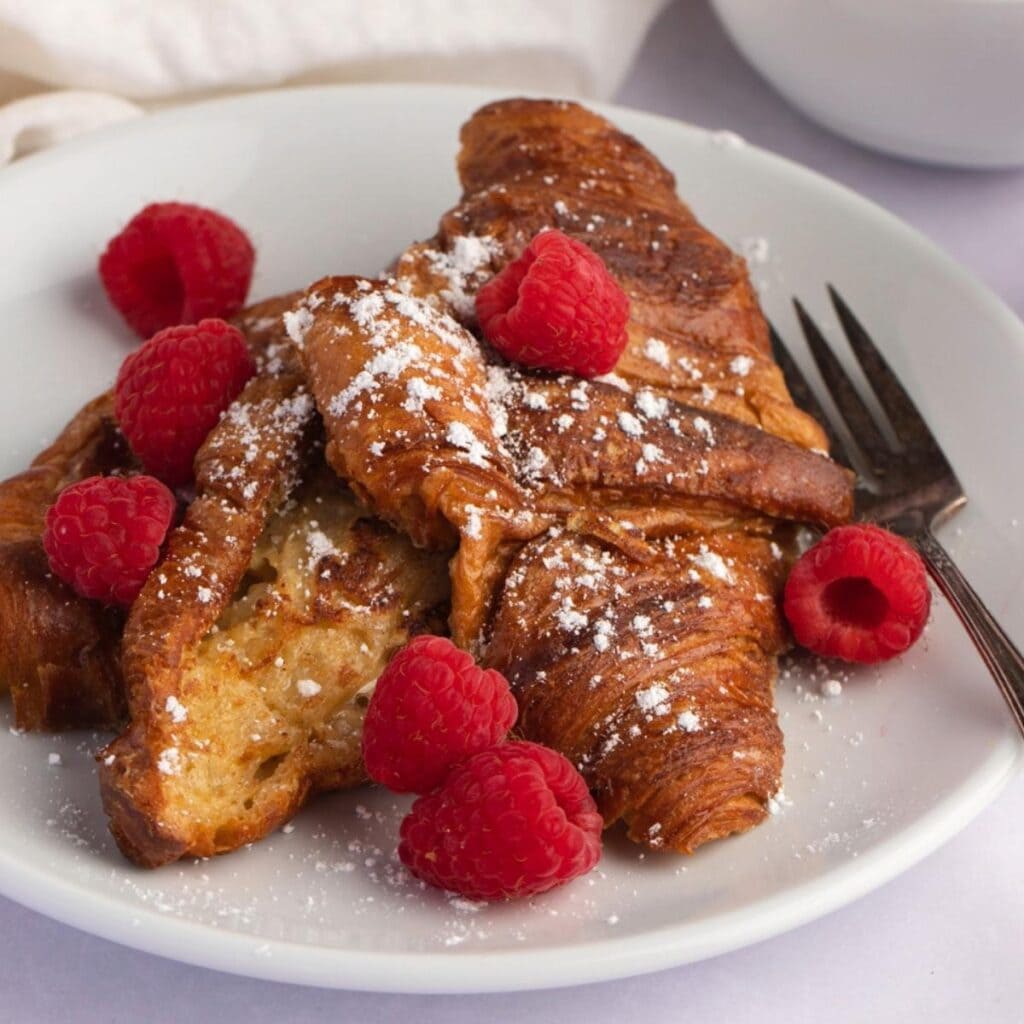 Buttery Croissant French Toast with Raspberries and Powdered Sugar