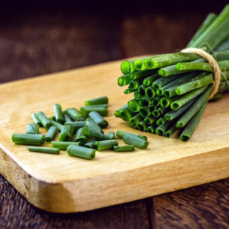 Fresh and Chopped Chives on a Wooden Chopping Board