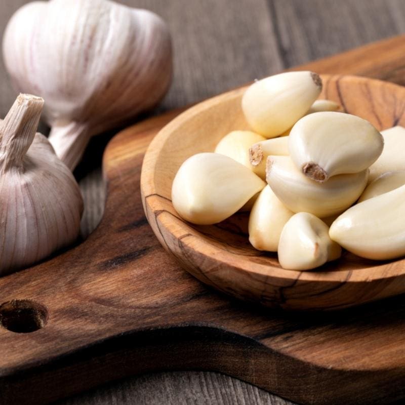 Whole and Peeled Garlic Bulbs on a Wooden Bowl
