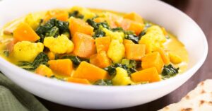 Homemade Pumpkin Curry with Spinach and Cauliflower in a White Plate