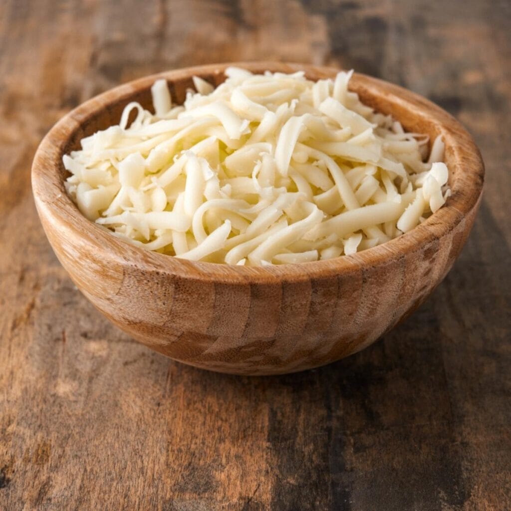 Grated Mozzarella Cheese on a Wooden Bowl