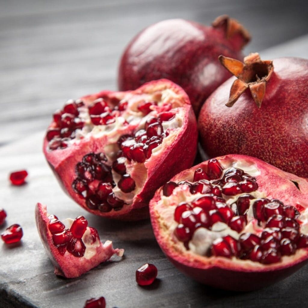 Whole and Sliced Into Half Pomegranate Lying on a Wooden Table