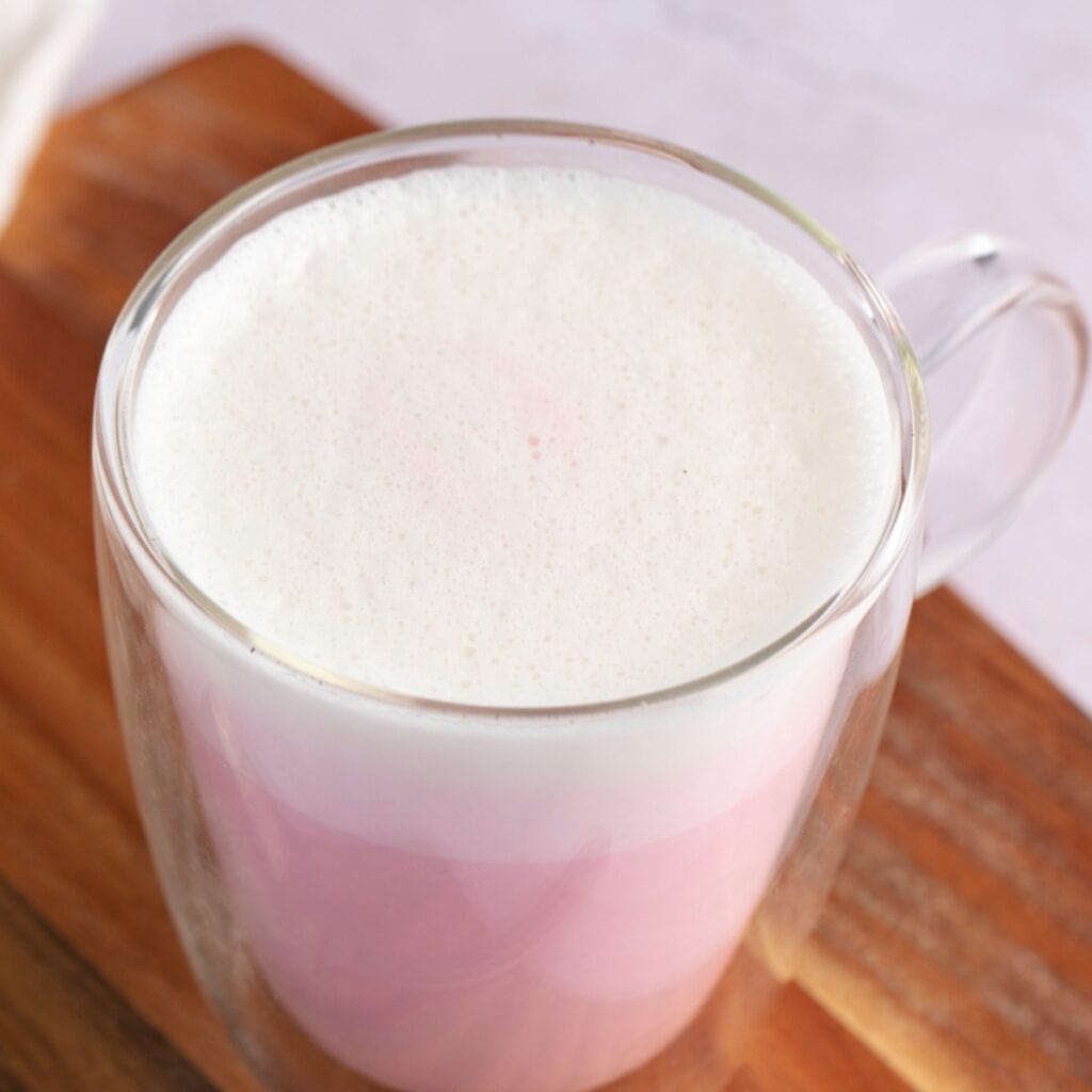 Glass mug of pink Angel Milk with foam