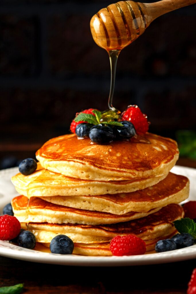 Fluffy Oatmeal Pancakes Topped With Berries and Drizzled With Honey 