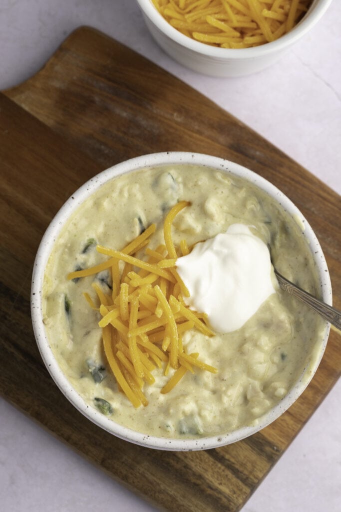 Green Chile Chicken Soup with sour cream and cheddar cheese on top