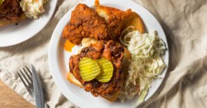 Homemade Nashville Hot Chicken with Pickles, Coleslaw and Bread in a White Plate