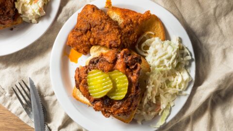 Homemade Nashville Hot Chicken with Pickles, Coleslaw and Bread in a White Plate