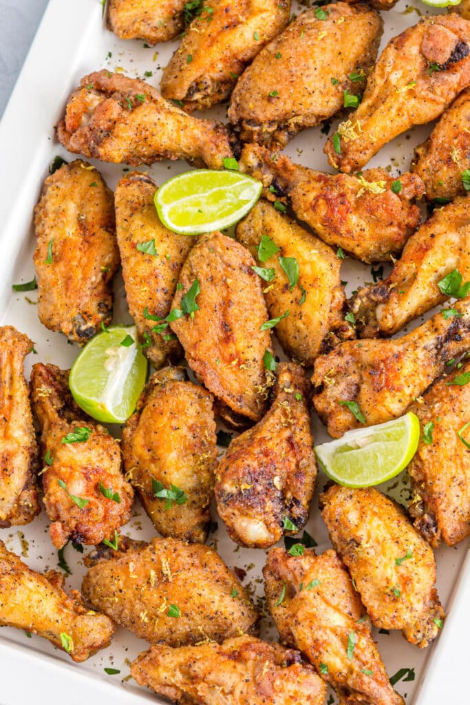 Lemon Pepper Chicken Wings on a tray with lime wedges