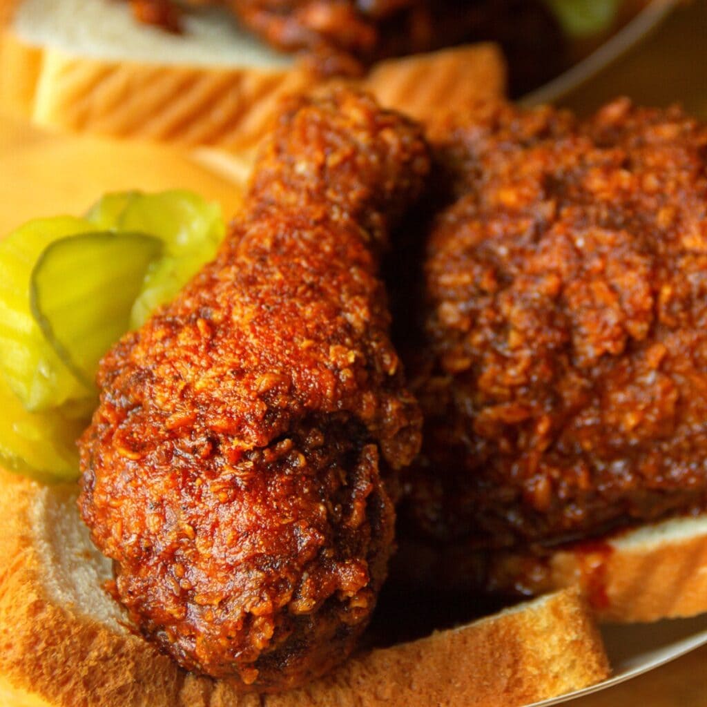 Nashville Hot Chicken served on white loaf bread garnished with pickles