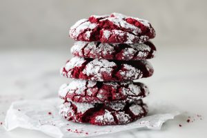 Stack of Red Velvet Crinkle Cookies on Parchment on a White Marble Table