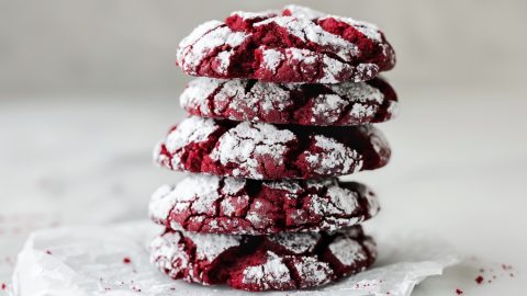 Stack of Red Velvet Crinkle Cookies on Parchment on a White Marble Table