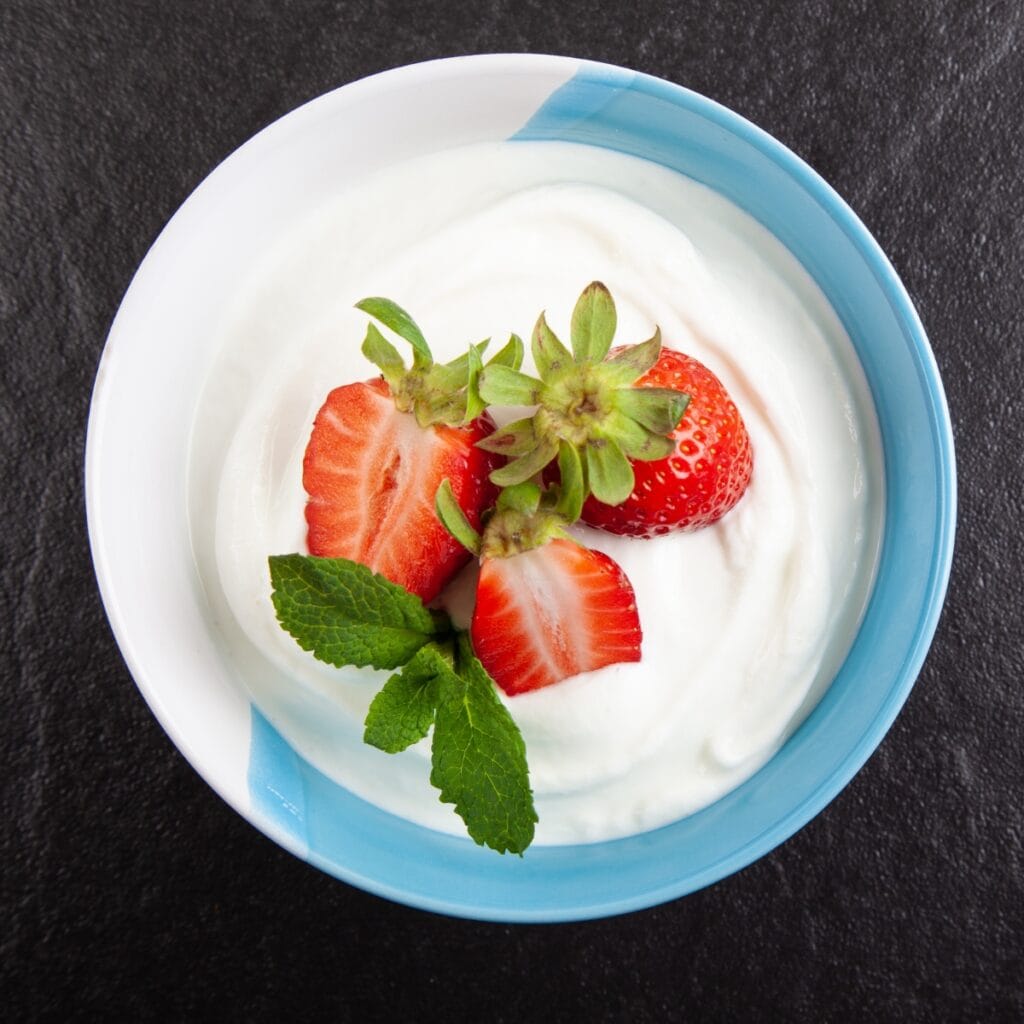 Skyr yogurt in a bowl with fresh strawberries and mint