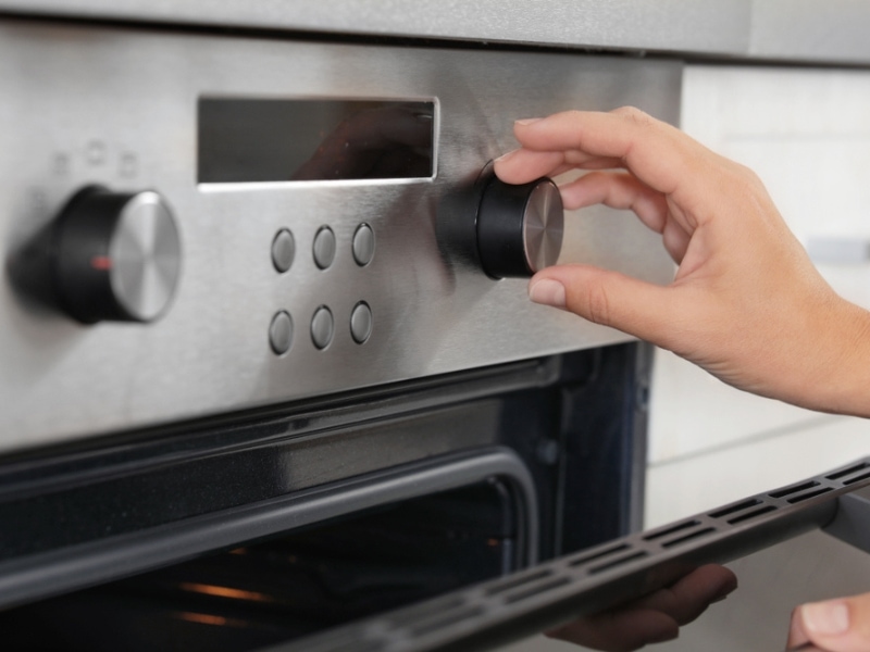 Open oven with hand turning a dial
