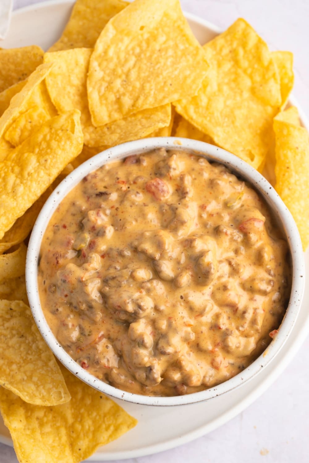 A white bowl filled with Rotel dip, served with tortilla chips.