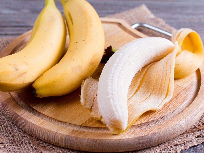 Peeled and Whole Bananas on a Round Wooden Tray