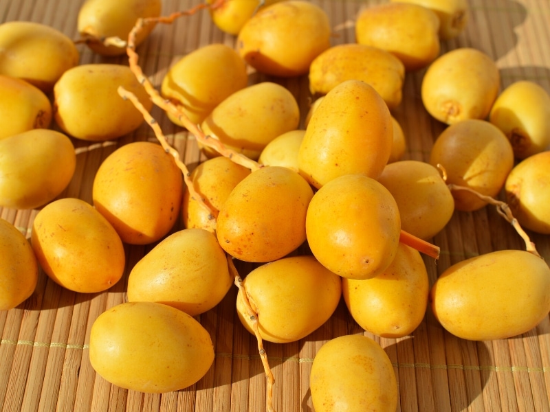 Bunch of Fresh Barhi Dates on a Bamboo Table
