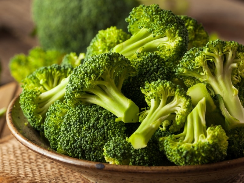 Bunch of fresh raw broccoli on a wooden bowl.