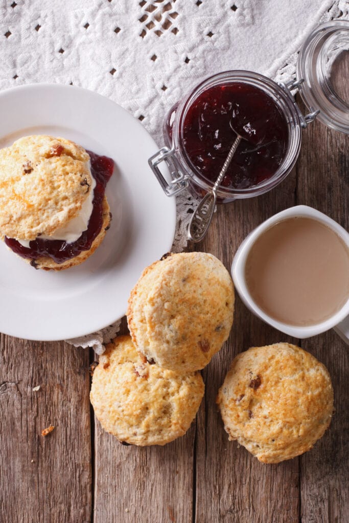 Scones on wooden table with tea and jam