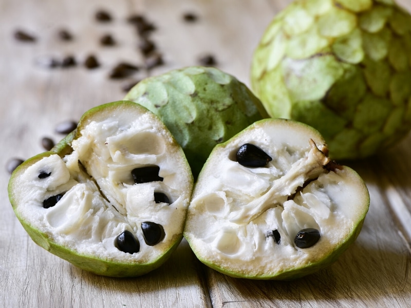 Whole and Sliced Cherimoya on a Wooden Table