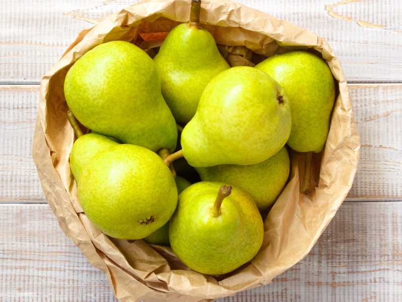 Green Pears in a Paper Bag on a Wooden Table