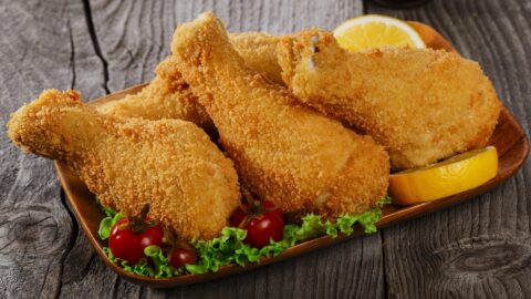 Homemade Breaded Fried Chicken Legs with Lemon, Tomatoes and Lettuce