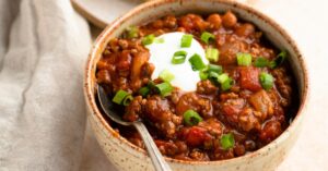 Homemade Chili with Sour Cream, Green Onions and Tomatoes in a Bowl