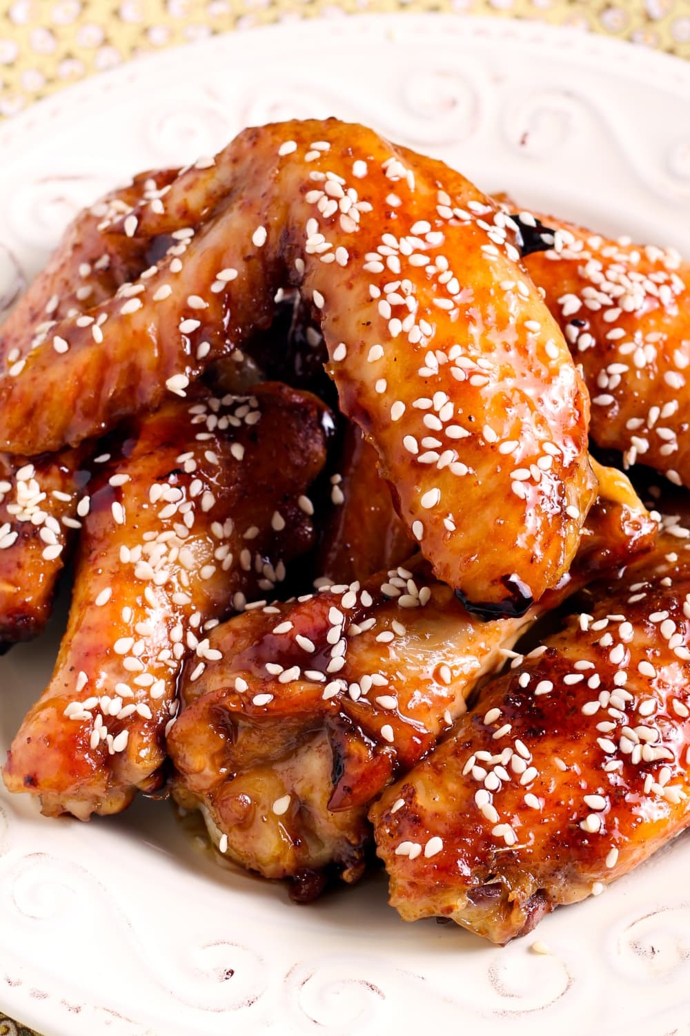 Honey sriracha chicken wings served on white plate sprinkled with sesame seeds. 