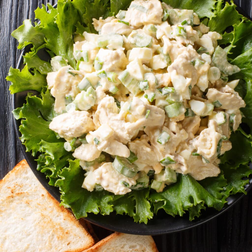 Ina Garten’s Chicken Salad Served on Top of Fresh Lettuce Laid on a Black Bowl
