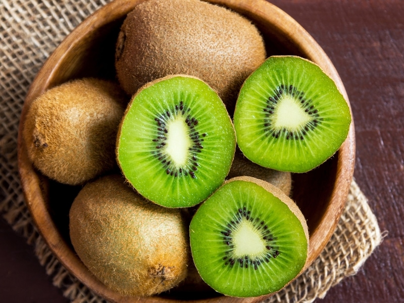 Kiwi Whole and Half in a Round Wooden Bowl