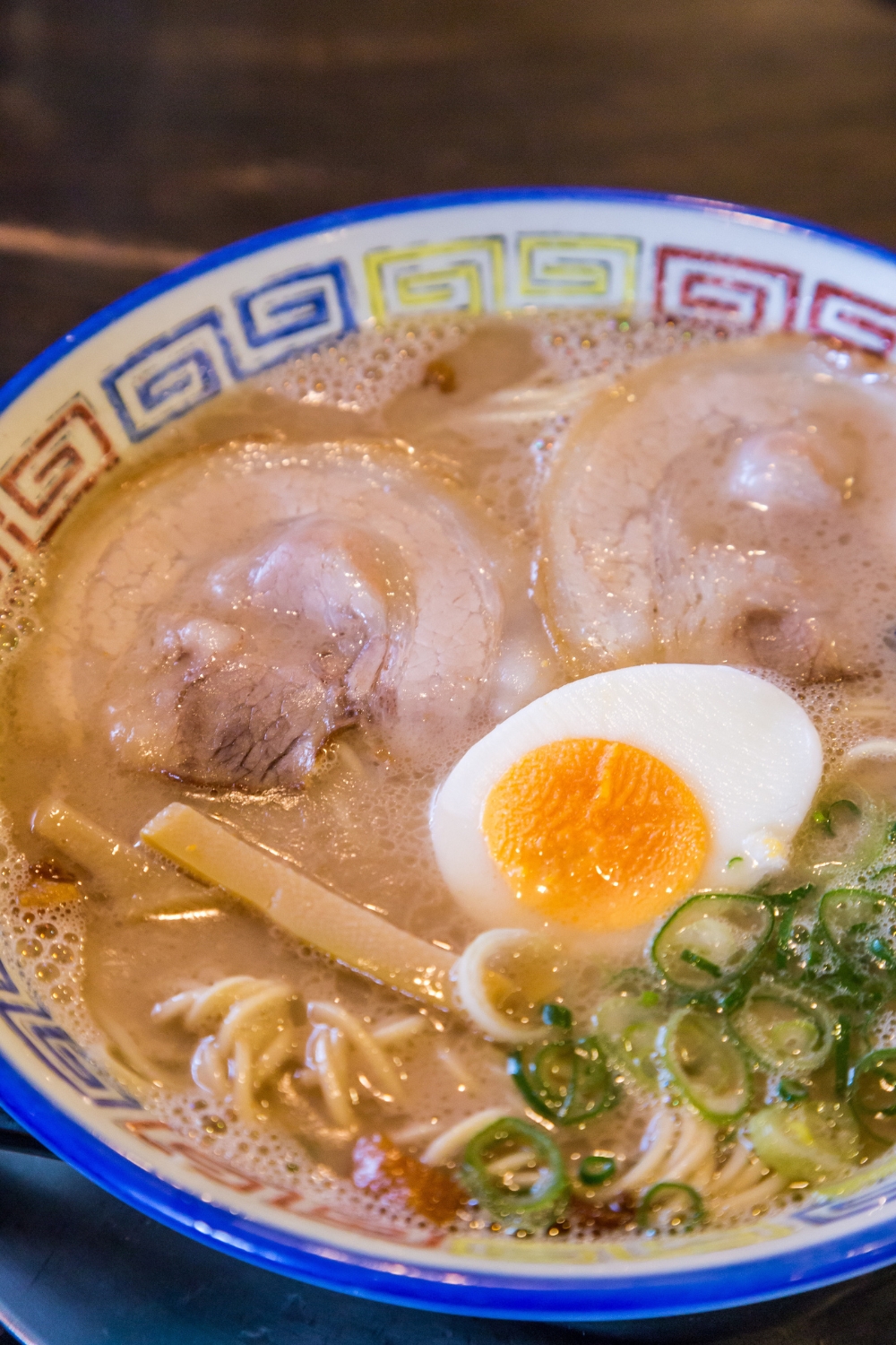 Kurume ramen served in a traditional Japanese bowl made with soup, noodles, sliced meat, egg, mushroom and chives. 