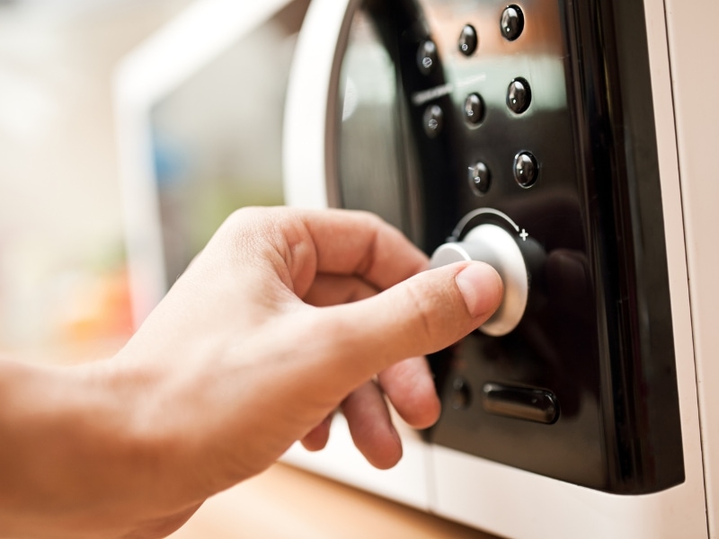 A Person Turning on a Microwave Oven