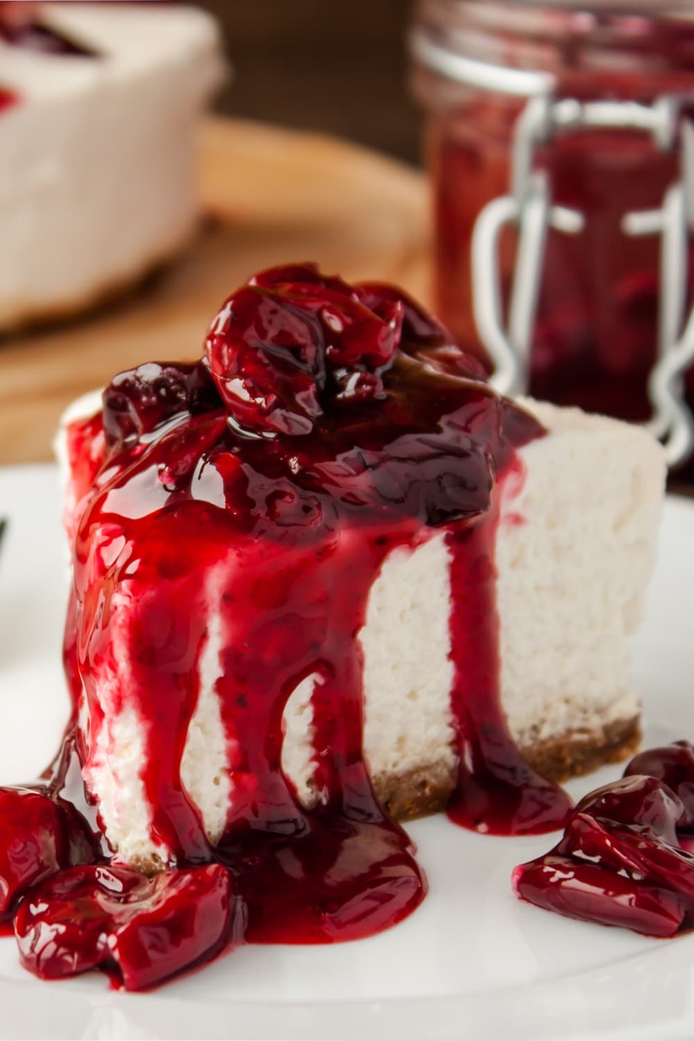 Slice of No-Bake Cherry Cheesecake Dripping With Cranberry Sauce