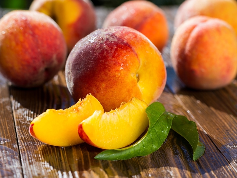 Whole and Peaches Slices on a Wooden Table