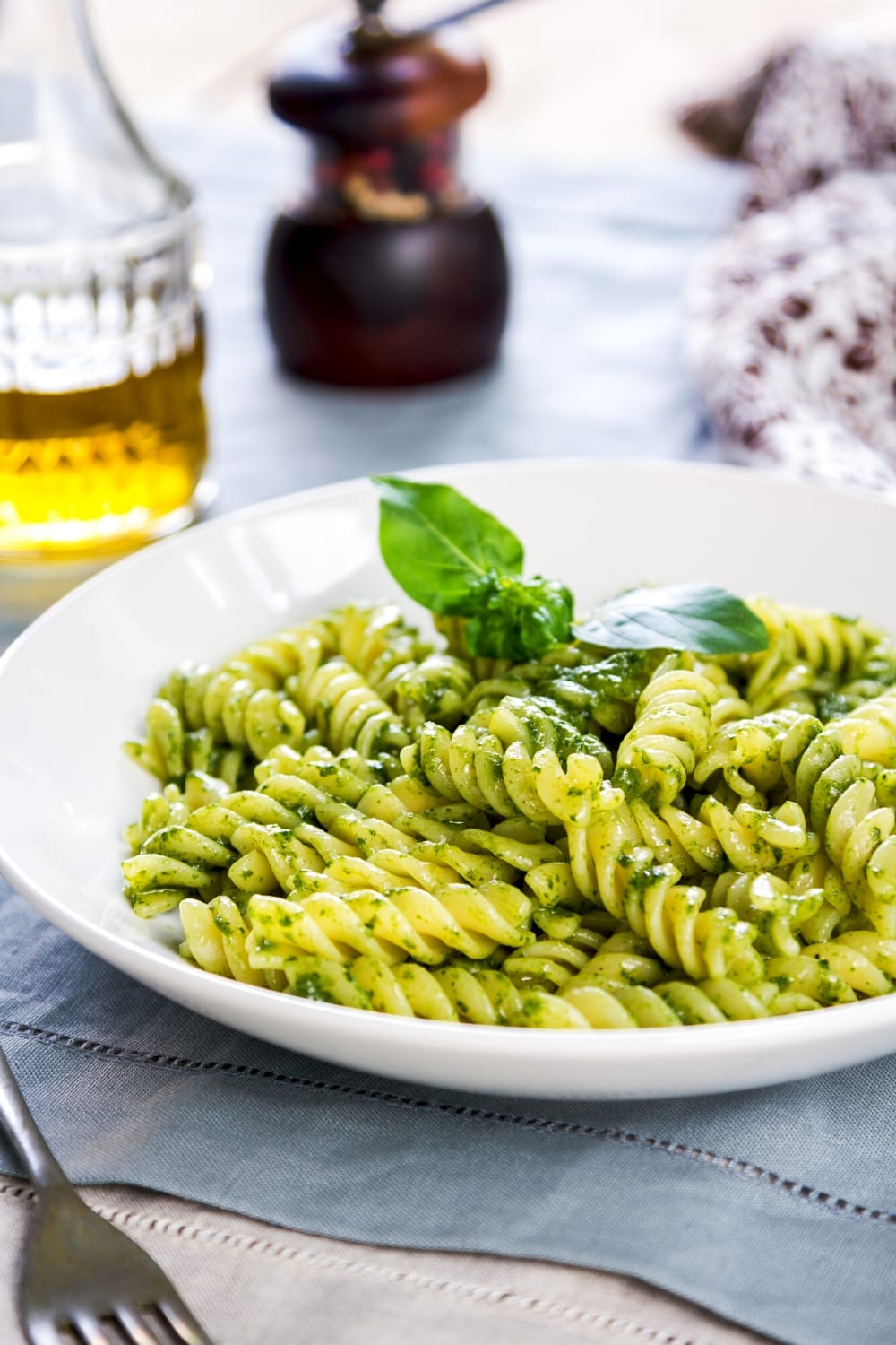 Spiral pasta with pesto sauce garnished with basil leaves. 