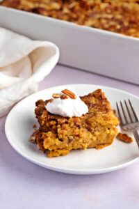 Pumpkin Pie Crunch Casserole with Whipped Cream and Pecan Nuts on a Plate