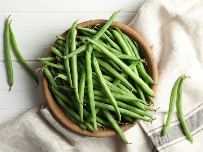 Top view of string beans on a wooden bowl.